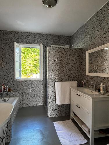 a bathroom with a sink and a tub and a window at La Casita in Mimizan
