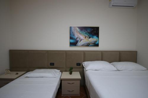 two beds in a room with a painting on the wall at Vila Bajrami in Vlorë