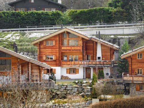 a large wooden house with a bridge in the background at Chalet Le Grillon by Interhome in Nendaz