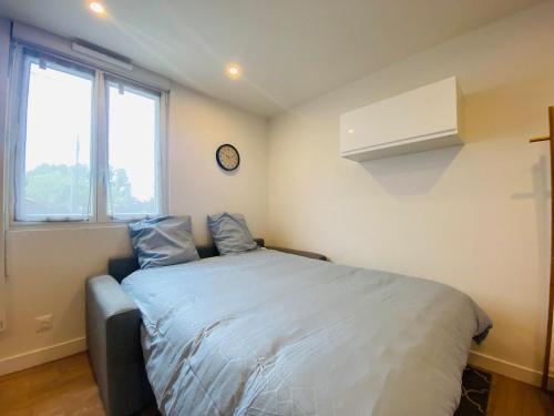 une chambre avec un lit et une horloge au mur dans l'établissement Casa Jacques, à Angers