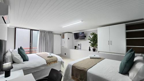 イースト・ロンドンにあるVincent Valley Lodgeの白いベッドルーム(ベッド2台、テレビ付)