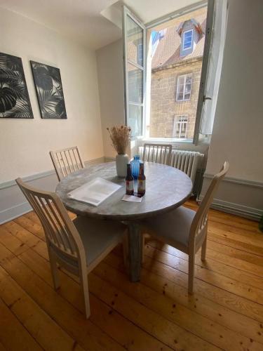une table de salle à manger avec des chaises et une grande fenêtre dans l'établissement Le Grilleton, à Dole