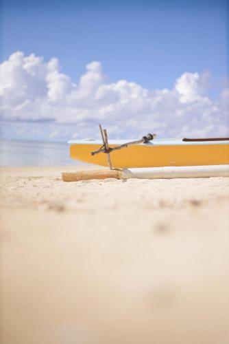 a yellow surfboard sitting on a sandy beach at Tamanu Beach in Arutanga