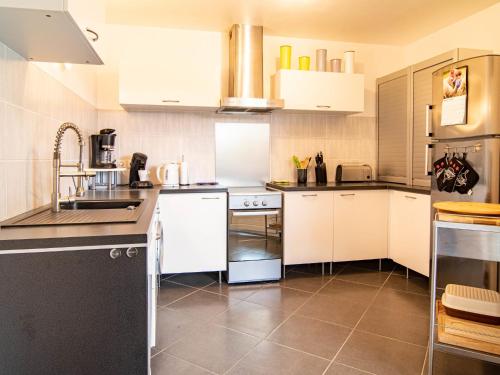 une cuisine avec des armoires blanches et des appareils noirs dans l'établissement Holiday Home Au Romarin by Interhome, à Bagnols-en-Forêt