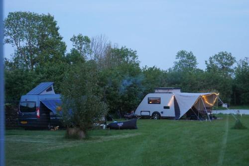 a couple of tents and a camper and a trailer at Hoeve Zorglust, salonwagen voor 2 personen met extra slaapkamerhuisje voor 2 - 3 kinderen in Koudekerke