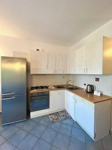 a kitchen with white cabinets and a stainless steel refrigerator at Residenza Le Spiagge in Sperlonga