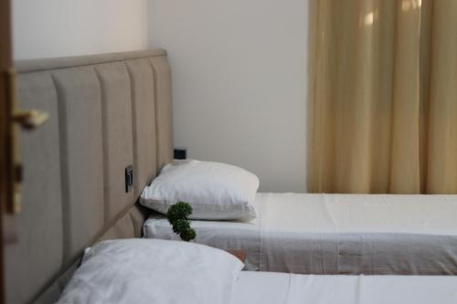two beds with white sheets and a potted plant on them at Vila Bajrami in Vlorë