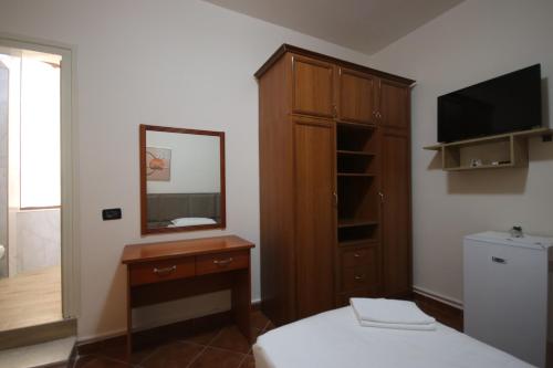a bedroom with a dresser and a mirror and a bed at Vila Bajrami in Vlorë
