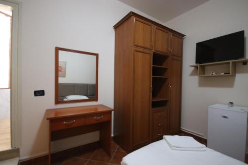 a bedroom with a dresser and a mirror and a bed at Vila Bajrami in Vlorë
