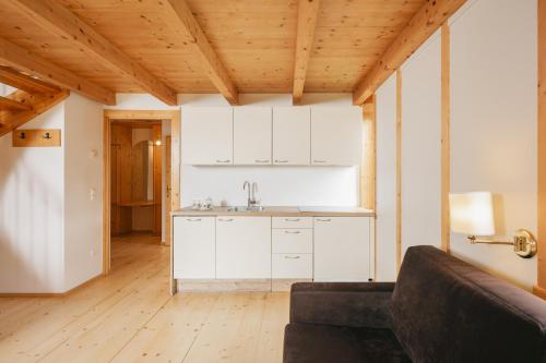 a kitchen with white cabinets and a couch in a room at Naturhotel Landhof Irschen in Irschen