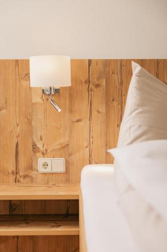 a bed with a lamp on a wooden wall at Naturhotel Landhof Irschen in Irschen