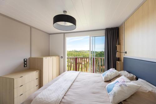 a bedroom with a large bed with a large window at Oihana grand chalet de 2 à 6 pers climatisé avec piscine vue et calme à Hasparren-Pays Basque in Hasparren