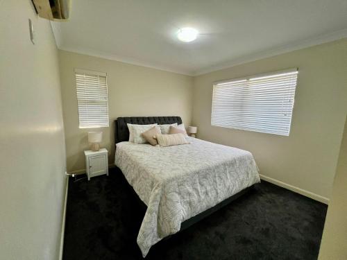 a bedroom with a bed and two windows at Blue Sky Gardens-minutes to JCU University &Townsville Hospital in Ross River