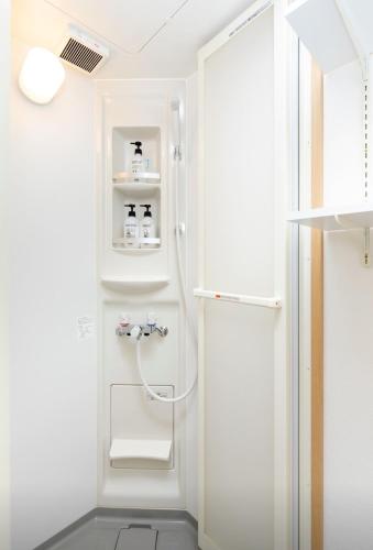 a bathroom with a shower and a white refrigerator at Osaka Family Villa with Free Parking near Namba in Osaka