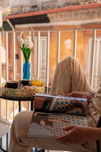 a person sitting on a chair reading a book at Maison S in Caserta