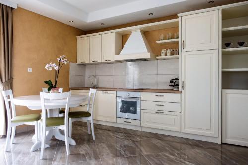 a kitchen with white cabinets and a table and chairs at Villa Barbara Apartments in Sumartin