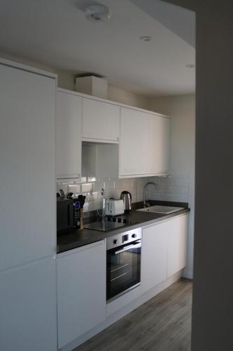 a white kitchen with white cabinets and a sink at Hector's Row in Tobermory