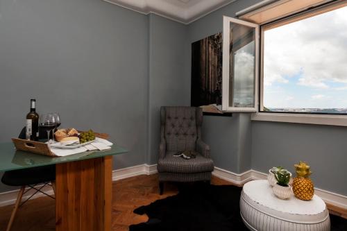 um quarto com uma mesa, uma cadeira e uma janela em Graça - Castle | Lisbon Cheese & Wine Apartments em Lisboa