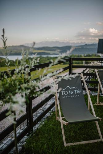 a chair sitting in the grass next to a fence at To Je To apartamenty in Maniowy