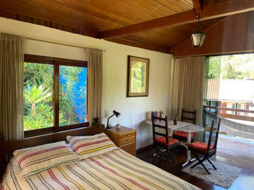 a bedroom with a bed and a table and chairs at Chalé aconchegante em Mury in Nova Friburgo