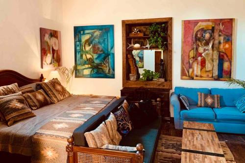 a bedroom with a bed and a blue couch at La Pajarera prime location in San Miguel in San Miguel de Allende