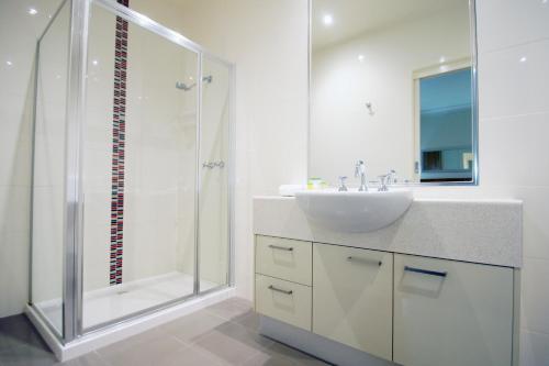 a white bathroom with a sink and a shower at The Wyndhamere Motel Shepparton in Shepparton