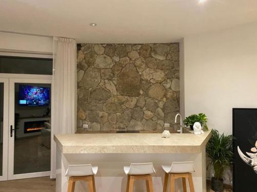 a kitchen with a stone wall and a counter with stools at Comfortable loft and great location in San Miguel de Allende