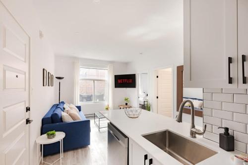a kitchen with a sink and a blue couch in a kitchen at Le Mile End by M11 - Modern 2BDR with Sofa Bed in Montréal