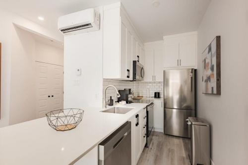 a kitchen with white cabinets and a stainless steel refrigerator at Le Mile End by M11 - Modern 2BDR with Sofa Bed in Montréal
