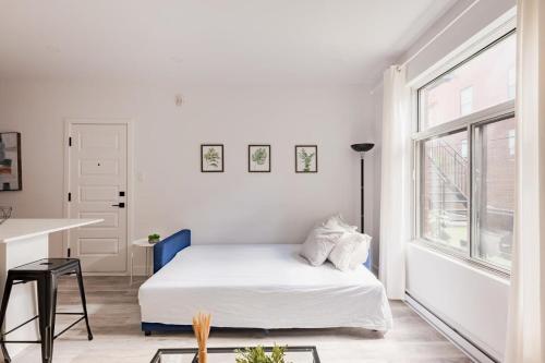 a white bedroom with a bed and a window at Le Mile End by M11 - Modern 2BDR with Sofa Bed in Montréal