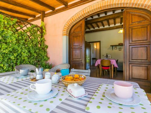 a table with cups and a bowl of fruit on it at Apartment Bianco by Interhome in Suvereto