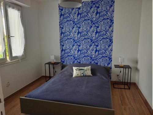 Ce lit se trouve dans un dortoir doté d'un mur bleu et blanc. dans l'établissement Bord de mer, à Ploemeur