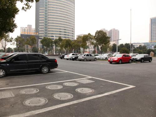 a parking lot with cars parked in a city at Jinjiang Inn Taicang Shanghai Road in Taicang