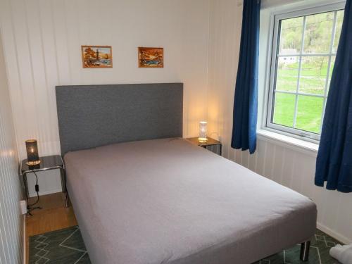 a bedroom with a bed with blue curtains and a window at Holiday Home Greenhouse by Interhome in Onarheim