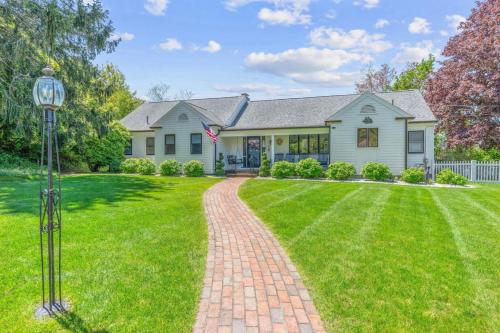a house with a brick driveway in front of a yard at Stunning Waterfront Home with Hot Tub Deck Fire Pits and Office in Dennis