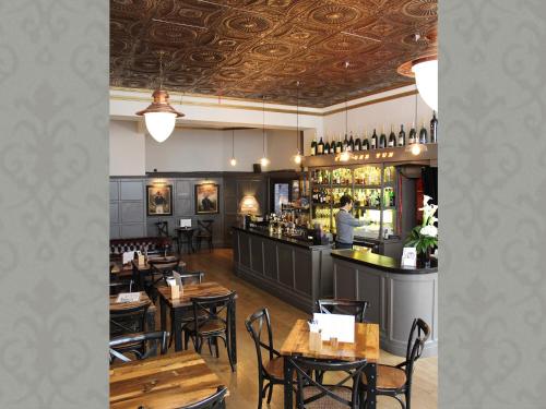 a restaurant with tables and a bar with a bartender at The One Tun Pub & Rooms in London