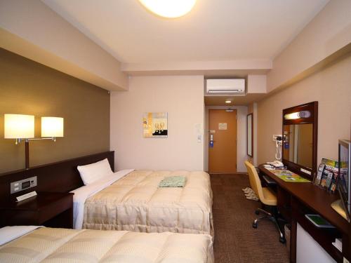 a hotel room with two beds and a desk at Hotel Route-Inn Utsunomiya Miyukicho -Kokudou4gou- in Utsunomiya