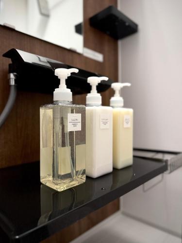 three bottles of soap sitting on a black shelf at SATELLITE HOTEL Roppongi サテライトホテル六本木 in Tokyo