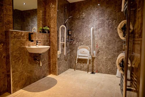 a bathroom with a sink and a shower with a chair at The Enniskillen Hotel and Motel in Enniskillen