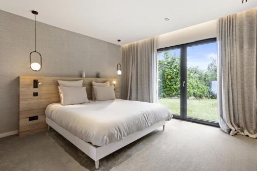 a bedroom with a white bed and a large window at Villa Belenos Piscine vue mer in Saint-Peïre-sur-Mer
