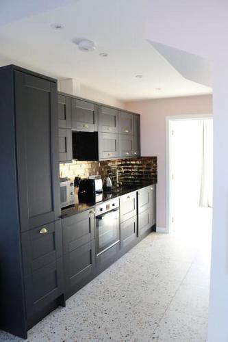 a kitchen with gray cabinets and a stove top oven at Hector's Row in Tobermory