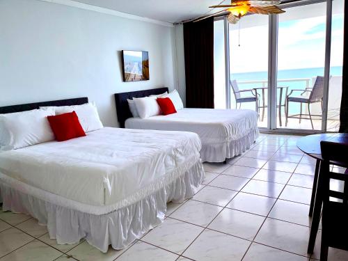 two beds in a room with a view of the ocean at Castle 1527 Studio Balcony Direct Beach Access, Pool, Tennis, Free Parking in Miami Beach