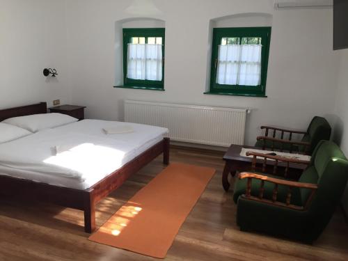 a bedroom with a bed and a couch and a chair at Pincesor Apartman in Villánykövesd
