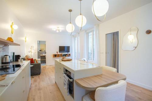 une cuisine avec des armoires blanches et une table dans une pièce dans l'établissement Montmartre Rochechouart - 1 Bed Apt Sleeps 2, à Paris