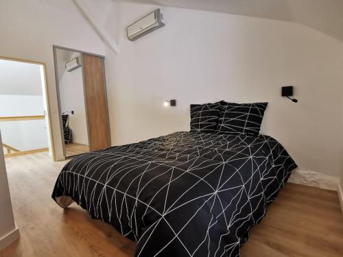 a black and white bed in a white room at gites des ammonites in Montalieu-Vercieu