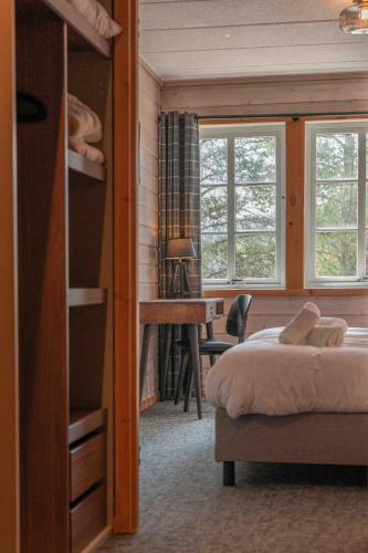 a bedroom with a bed and a desk and windows at Pollfoss Boutique Hotel & Spa in Skjåk
