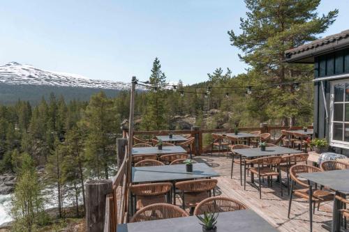 a deck with tables and chairs and a mountain at Pollfoss Boutique Hotel & Spa in Skjåk