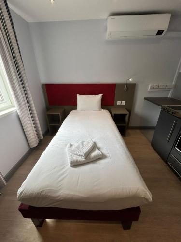 a bedroom with a white bed in a room with a red wall at London Walthamstow Hotel in London