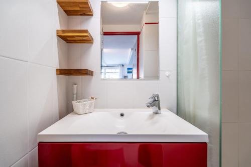 La salle de bains est pourvue d'un lavabo rouge et blanc et d'un miroir. dans l'établissement Maison 38m2 proche de la mer, à Gruissan