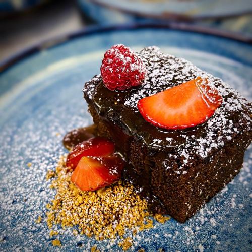 a piece of chocolate cake with a strawberry on a blue plate at The Enniskillen Hotel and Motel in Enniskillen